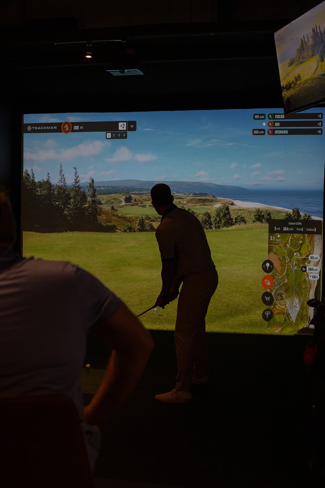 Golfer practicing indoors on a TrackMan-style mat